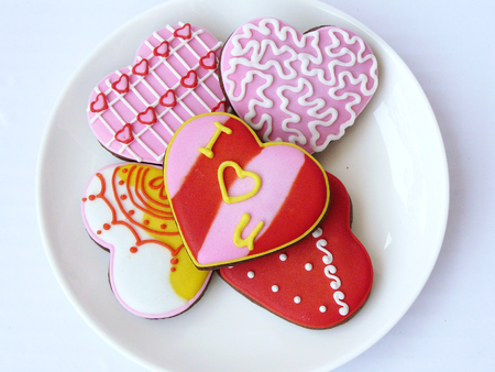 Chocolate lover cookie. Chocolate cookies in sweet heart shape decorated with colorful sugar close up top view on a white plate. Isolated on white background.の写真素材