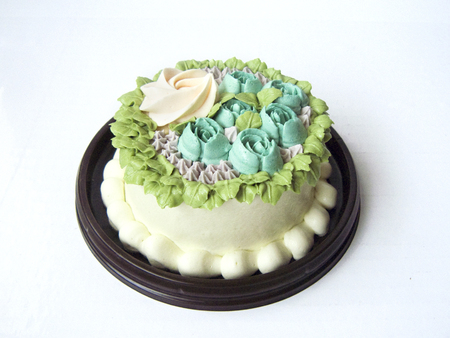 Close up top view of colorful sweet milky vanilla cake decorated with cream vanilla in rose garden pattern on a brown plate isolated on white background.の写真素材