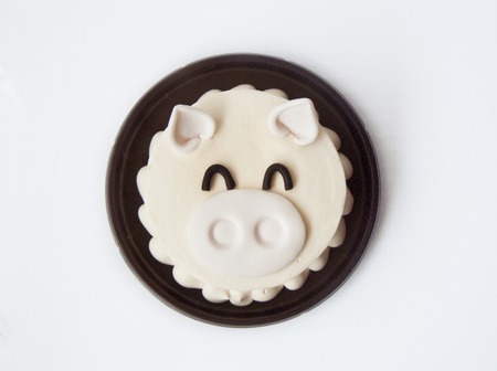 Delicious sweet cute piglet vanilla cream cake. The vanilla cake decorated with cream sugar color in a shape of cartoon style. Close up top view on a brow plate, isolated on background.の写真素材