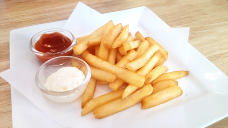 Eating happy snack: Delicious french fries with 2 sauce, ketchup and mayonnaise on a white plate.の写真素材