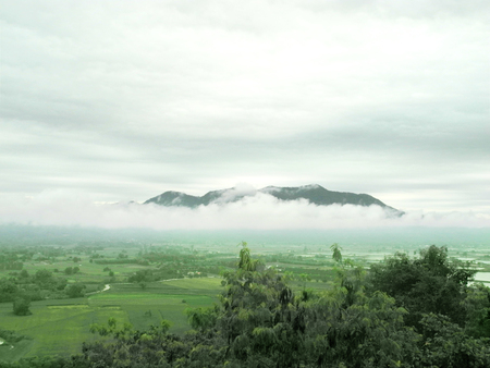 Scenery from top of mountain, can seen a plain of green paddy and a big dark mountain in the mystery mist. Beautiful landscape at the north of Thailand.の写真素材