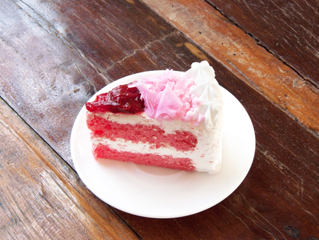 Delicious strawberry cream cake, The layer strawberry cake decorated with cream and jam strawberry in a white plate. Close up side view on wooden table background.の写真素材