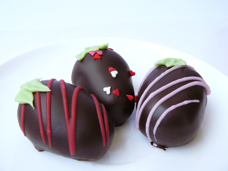 Trio Chocolate ball decorated with colorful sugar topping seem like strawberry in paper cup and red love ribbon in a white plate isolated on white background.の写真素材