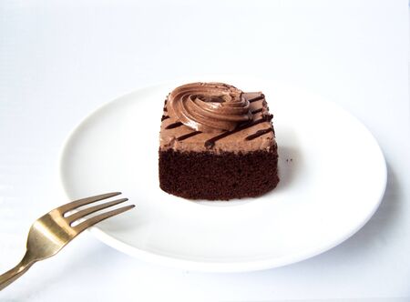 Delicious sweet Chocolate cream cake. Close up front view of a chocolate cake decorated with chocolate cream cut on a white plate, Isolated on white background.の写真素材