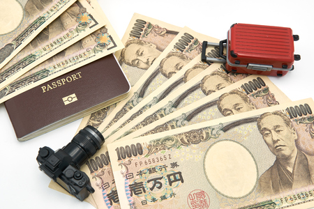 Camera model Red luggage model passport And 10000 yen banknotes placed on a white background. Communicates travel planning to Japan.の写真素材