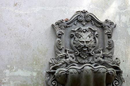 Old Lion Head Fountain, which is mounted on a white-gray wall. Which is not used for a long time, do leaves covered. See the whole garden. copy spaceの写真素材
