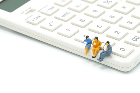 Miniature 3 people sitting on white calculator using as background business concept with copy space.の写真素材