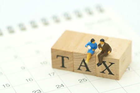 Miniature people Pay Annual income (TAX) for the year on Calendar using as background business concept and finance concept with copy space  for your text or  design.の写真素材