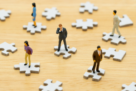 Miniature people businessmen standing on white Jigsaw. The concept used in selecting personnel to participate in the organization. with copy space.の写真素材