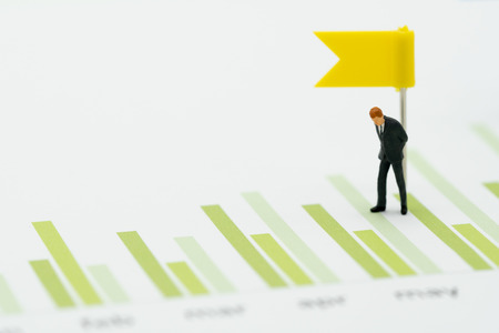 Miniature people businessmen standing Investment Analysis Or investment Sales rankings are targeted to determine the flag. using as background business concept with copy space and white space.の写真素材