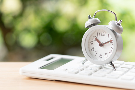 Vintage White Alarm Clock placed on a white calculator using as background business concept and...