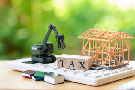 A model house model is placed on wood word TAX . as background property real estate concept with copy space for your text or  design.の写真素材