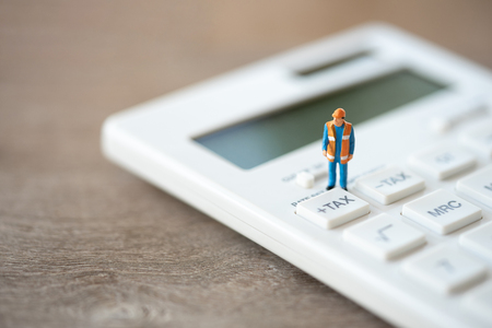 Miniature people Construction worker Keypad TAX button For tax calculation. Easy to calculate. on White calculator on white background using as background business concept and with copy space.の写真素材