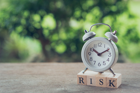 Vintage White Alarm Clock placed on wood word RISK. The concept of risk diversification of a business or organization. For the unexpected. as background business concept and strategy conceptの写真素材