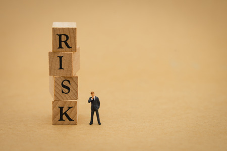 Miniature people businessmen standing with wood word RISK using as background business concept and Risk concept with copy space  for your text or design.の写真素材