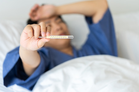 Asian handsome man Hypothermia has been measured by fever. Lie on the bed to give a body of...