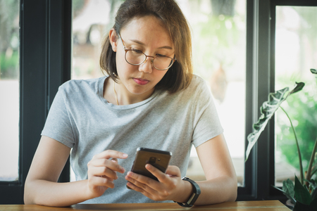 Asian girl Play smartphone For entertainment and work outside the office or outside. Out of Office Concepts Work wirelessly Communication in the modern world.の写真素材