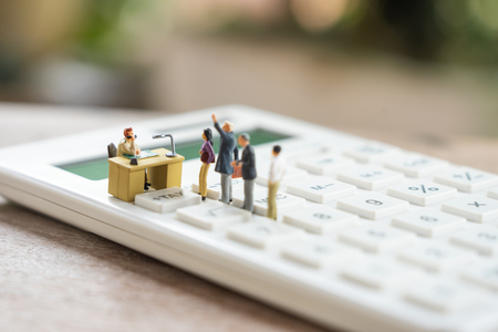 Miniature people Pay queue Annual income (TAX) for the year on calculator. using as background business concept and finance concept with copy space  for your text or  design.の写真素材