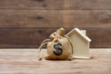 A model house model is placed on a pile of coins.using as background business concept and real...