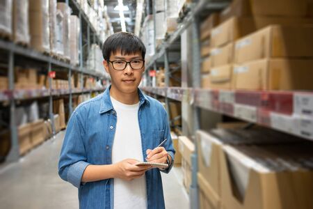 Portrait Asian men, staff, product counting Warehouse Control Manager Standing, counting and inspecting products in the warehouseの写真素材