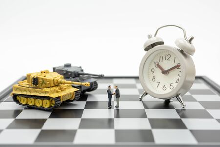 Miniature 2 people businessmen Shake hands standing on a chessboard with a chess piece on the back Negotiating in business. as background business concept and strategy concept with copy space.の写真素材