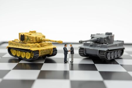 Miniature 2 people businessmen Shake hands standing on a chessboard with a chess piece on the back Negotiating in business. as background business concept and strategy concept with copy space.の写真素材