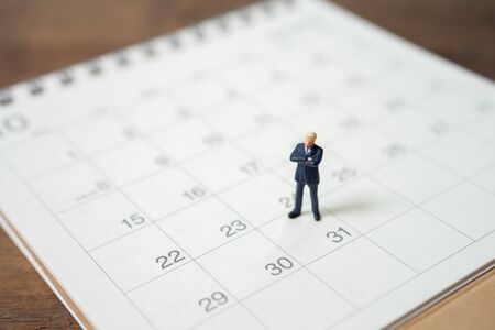 Miniature people businessmen standing on white calendar using as background business concept and finance concept with copy space  for your text or  design.の写真素材