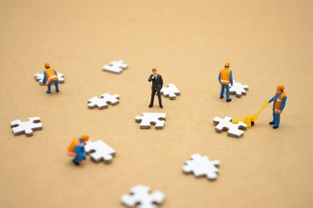 Miniature people businessmen standing on white Jigsaw. The concept used in selecting personnel to participate in the organization. with copy space.の写真素材