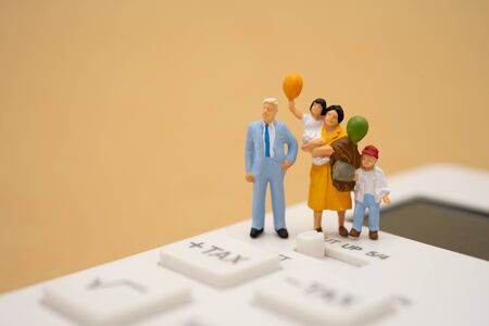 Family Miniature people Pay queue Annual income (TAX) for the year on calculator. using as background business concept and finance concept with copy space  for your text or design.の写真素材