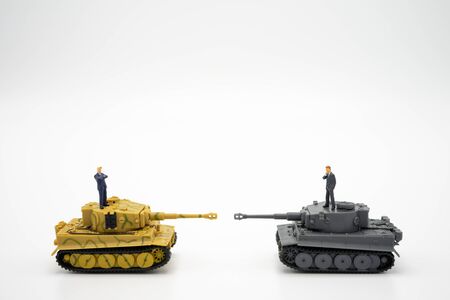 Miniature 2 people businessmen standing on Toy tank. Negotiating in business. as background Trade war, Trade protection, Political war, business concept and strategy concept with copy space.の写真素材