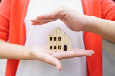 A model house model is placed on The Hands of Asian Business Girl.using as background business...