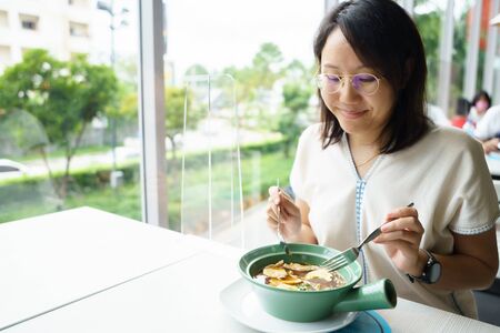 New normal Middle-aged Asian woman Eating food with a plastic plate to prevent the spread of the...