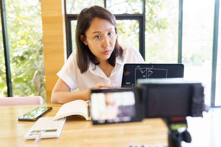 New normal Asian woman aged 30-35 years, vlogger coach presentation training people online. Webcam...