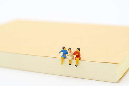 Miniature people sitting on notebook using as background business concept and teamwork concept with copy space and white space.の写真素材