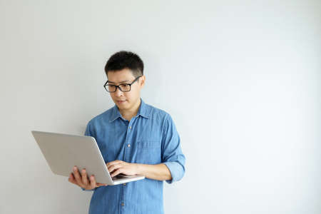 Side view Portrait of happy young businessman holding in hands laptop working at office. looking at laptop computer screen.の写真素材