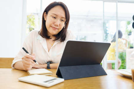 Asian woman aged 30-35 years using tablet, watching lesson online course communicate by conference...