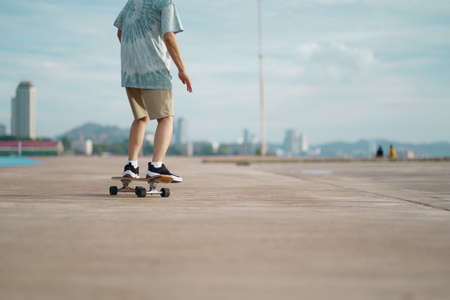 Asian having fun with surfboards or surf skate around city streets background on a summer day. Free relax lifestyle and millennial trend conceptの写真素材