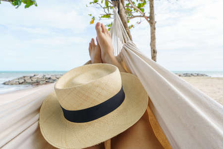 Hello Summer man relaxing in hammock tanning on the beach happy sunbathing during summer holidays. on tropical vacations.の写真素材