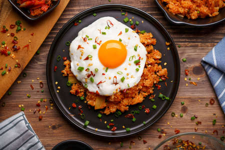 Kimchi Fried rice topped with fried egg and fresh kimchi cabbage in a bowl on placed wooden background. Korean food styleの写真素材