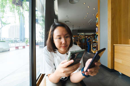 Asian girl Play smartphone For entertainment and work outside the office or outside. Out of Office Concepts Work wirelessly Communication in the modern world.の写真素材