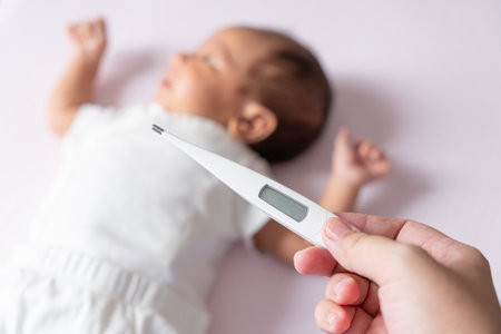 A mother gently checks her baby temperature with a thermometer, ensuring her little one is comfortable and healthy, with tender care and concern.の写真素材