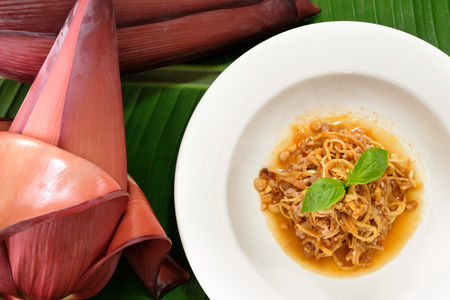Banana blossom salad in white dish on green banana leaf.の写真素材