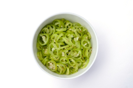 Green chilli cut in a white bowl top view isolated on white backgroundの写真素材
