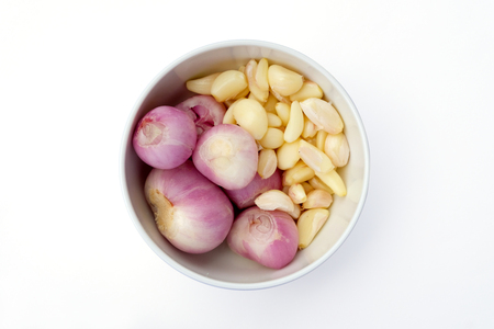 Onion and garlic in a white bowl top view isolated on white backgroundの写真素材