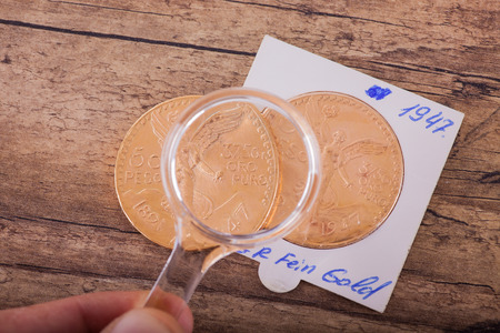 Two gold coins under magnifying glass