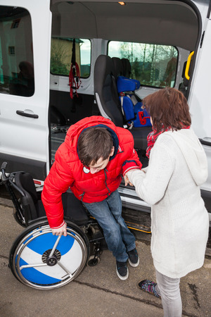 A mother helps her handicapped son off the school bus.の写真素材