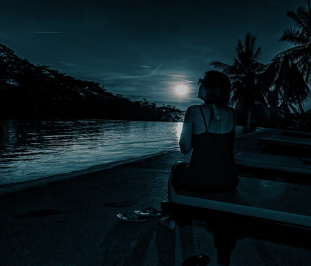 Woman at night in the moonlight at the sea.の写真素材