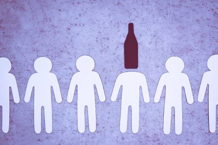 White paper figures of people stand in row. One man has bottle for head. Symbol of alcohol...