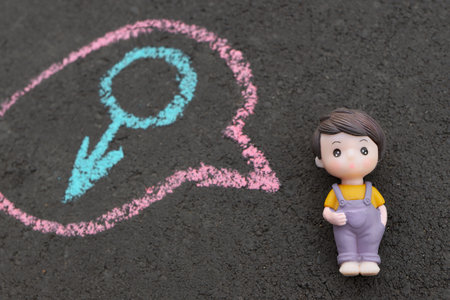 concept of growing up and gender awareness. boys toy lies on dark background. male symbol is drawn in chalk in mind.の写真素材
