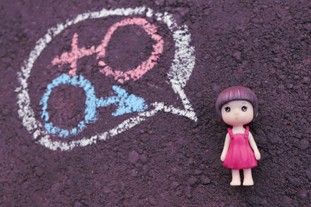 teen girl chooses between symbols of man and woman. Figurine on black background. concept of determining gender, growing up and becoming aware of body.の写真素材